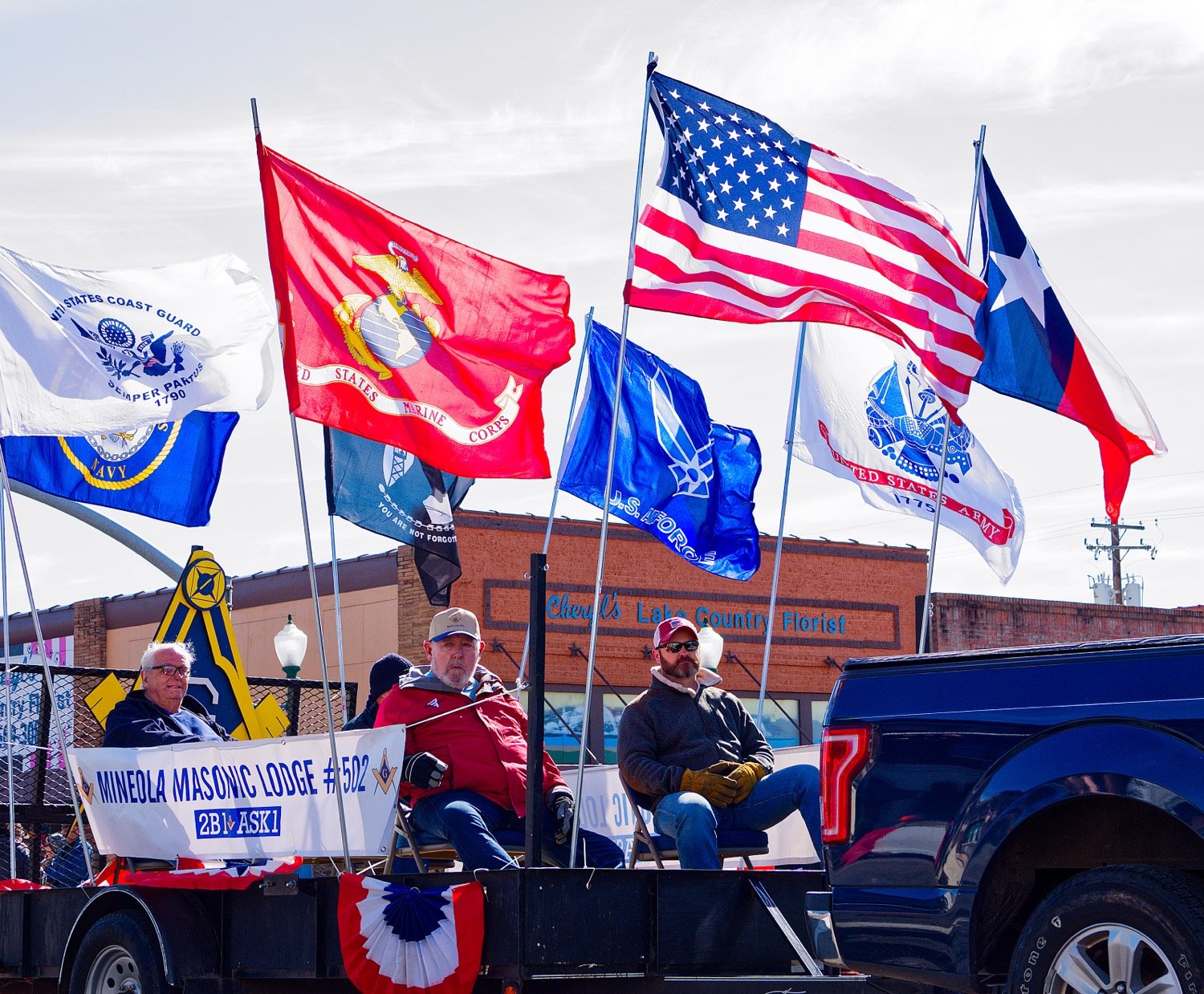 Flags representing branches of the armed forces wave from the perch of the Mineola Masonic Lodge #502 float. [view more vets]